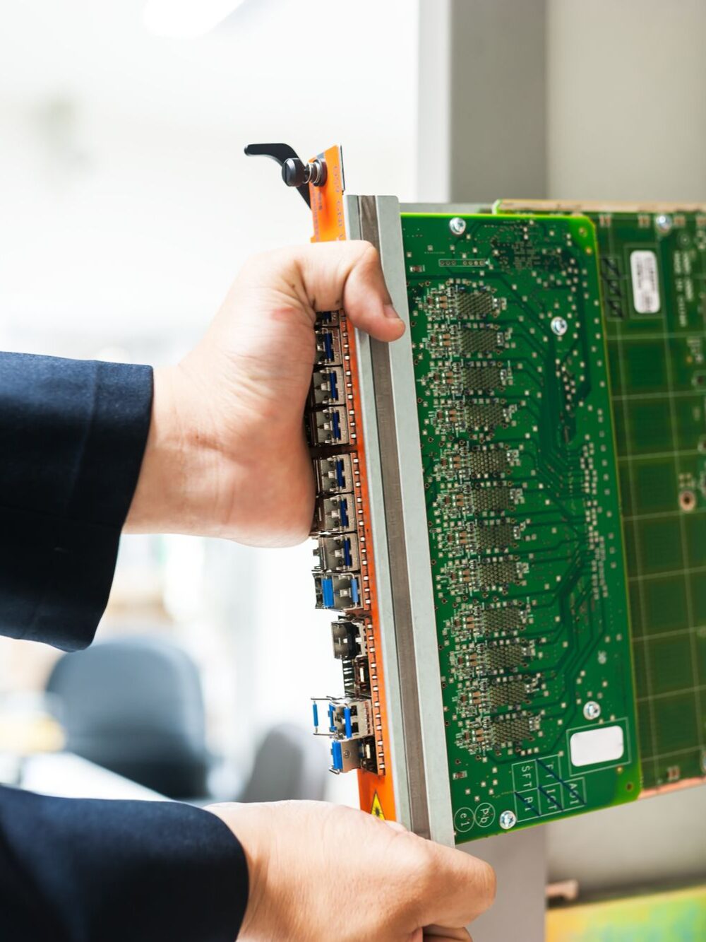 Técnico encaixando uma placa de rede em um chassi de equipamento.